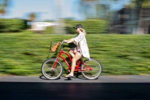 Woman Biking on sidewalk in front of green bushes with speed blur. Stock Photography Free for Commercial Use.