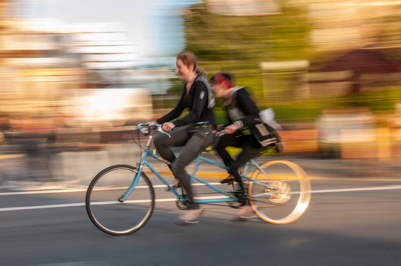 Two women on tandem bike in the fall, speed blur. Stock Photography Free for Commercial Use.