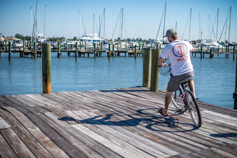 Image of biker on wooden dock overlooking the ocean and sailboats. Stock Photography Free for Commercial Use.