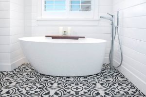 Beautiful white tub on patterned tile in bathroom with shower. Stock Photography Free for Commercial Use.