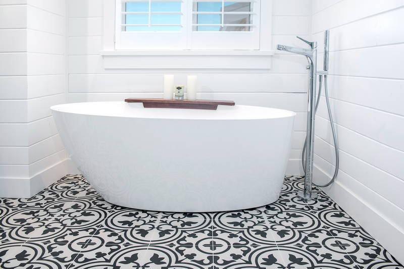 Beautiful white tub on patterned tile in bathroom with shower. Stock Photography Free for Commercial Use.