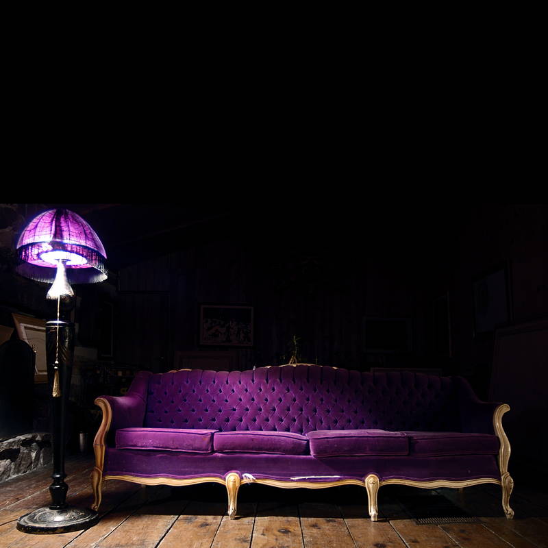 Purple couch under purple lamp with wooden hardwood floor, vintage retro velvet fabric couch. Stock Photography Free for Commercial Use.