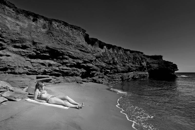 Beautiful woman on beach underneath cliff in bikini. Stock Photography Free for Commercial Use.
